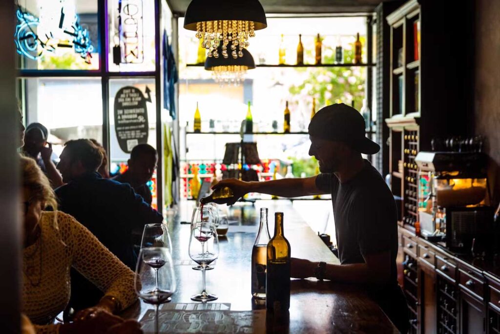 silhouette of a man in backwards baseball cap pouring wine behind the Gamling McDuck bar