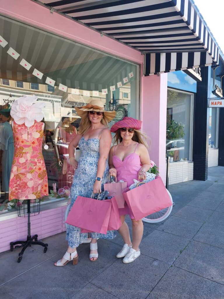 two women in hats with shopping bags outside of Muguette Renee