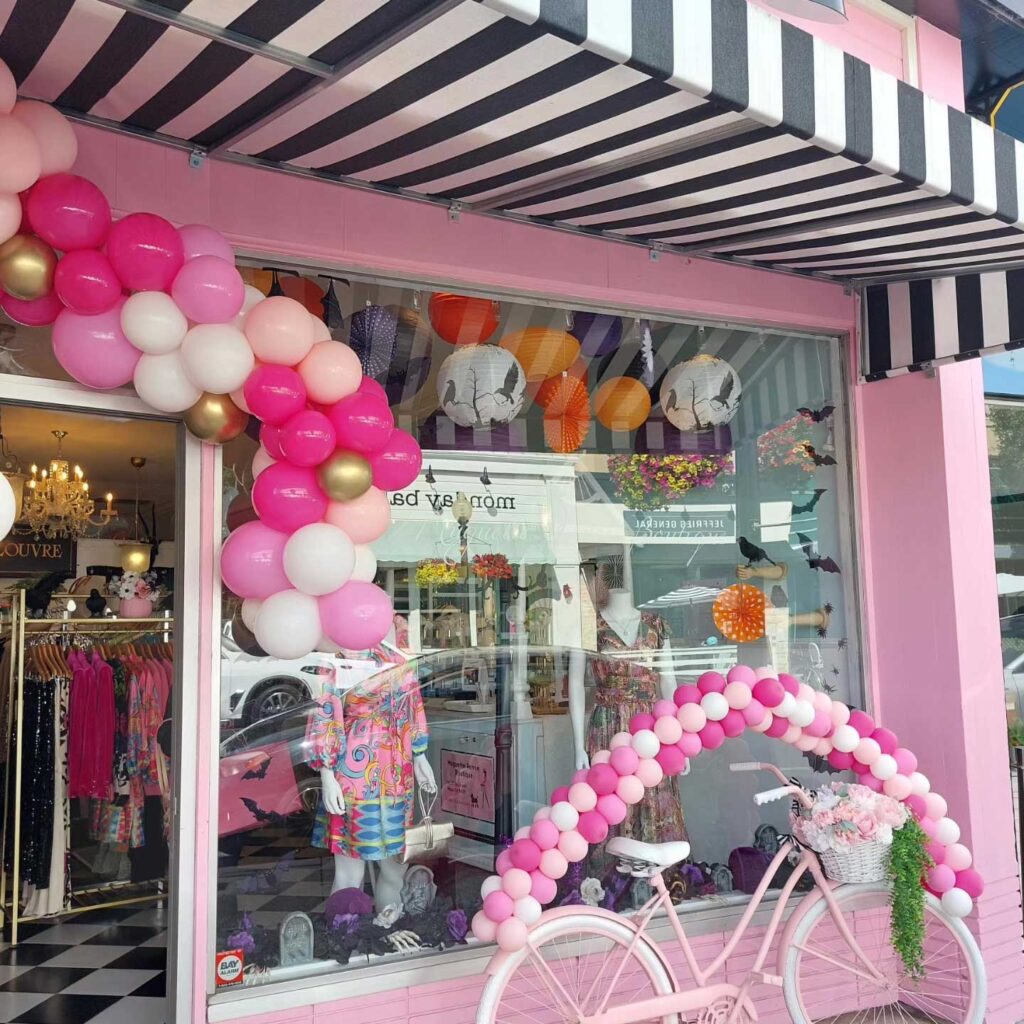 pink balloon arch over entry of Muguette Renee with pink bicycle out front