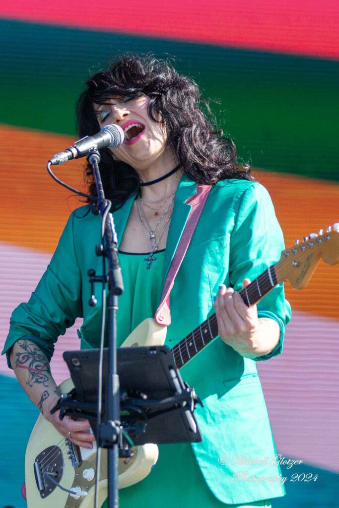 woman singing into microphone with guitar